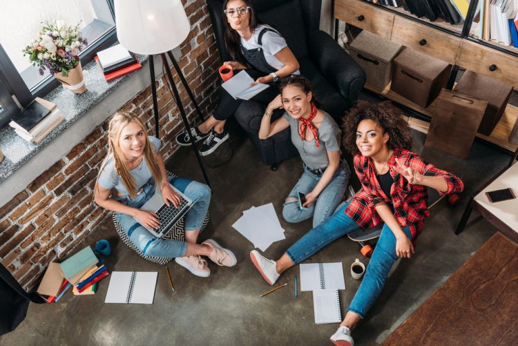 High angle view of attractive young women studying together and smiling at camera