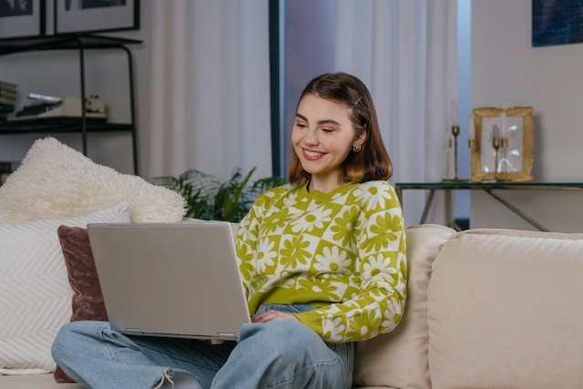 a woman sitting on a couch using a laptop computer